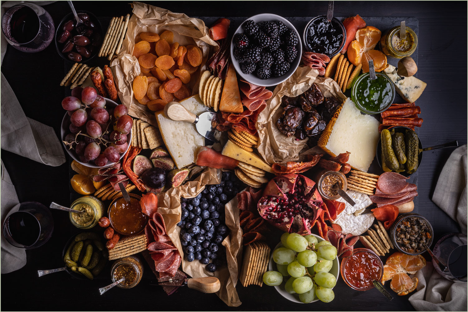 A giant charcuterie board with a variety of cured meats, cheeses, fruits, crackers and spreads.